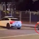 Horror moment self-driving taxi takes passengers into the middle of armed police standoff as cops aim guns at suspect